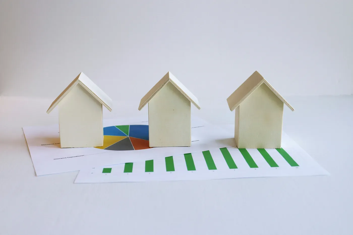 Small model houses arranged on printed financial charts, representing property valuation